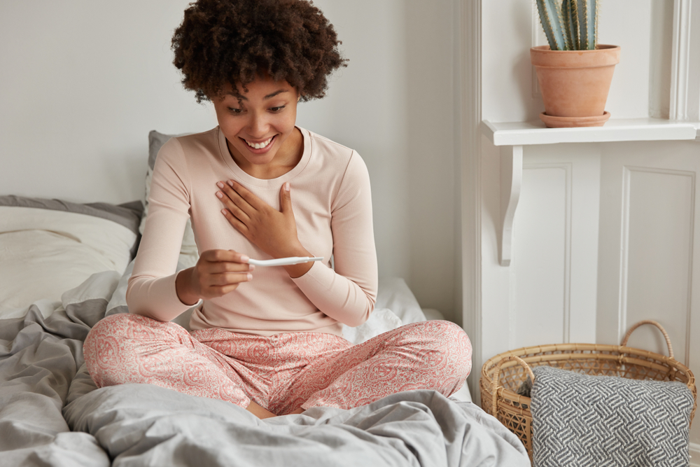 happy woman looking at positive pregnancy test