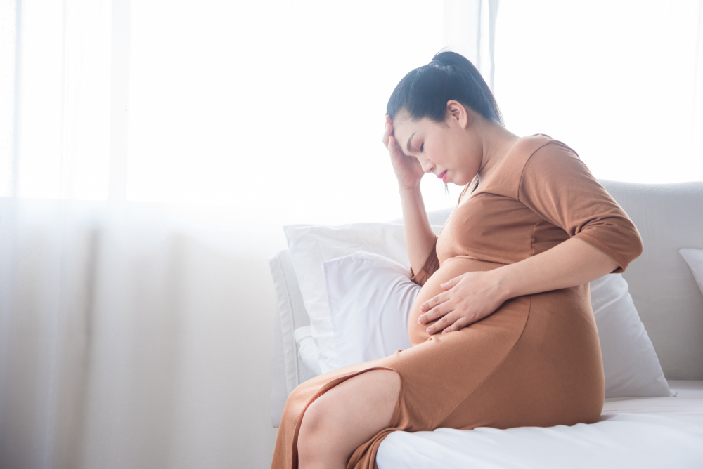 Middle aged pregnant woman sitting on bedMiddle aged pregnant woman sitting on bed